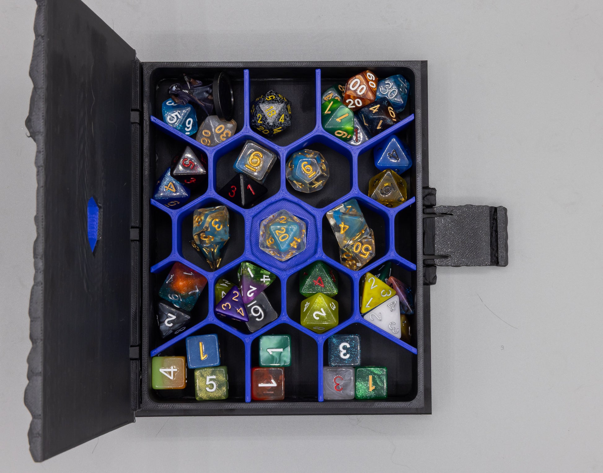 Dragon Dice Book open, displaying a polyhedral dice collection in the honeycomb tray — dice not included