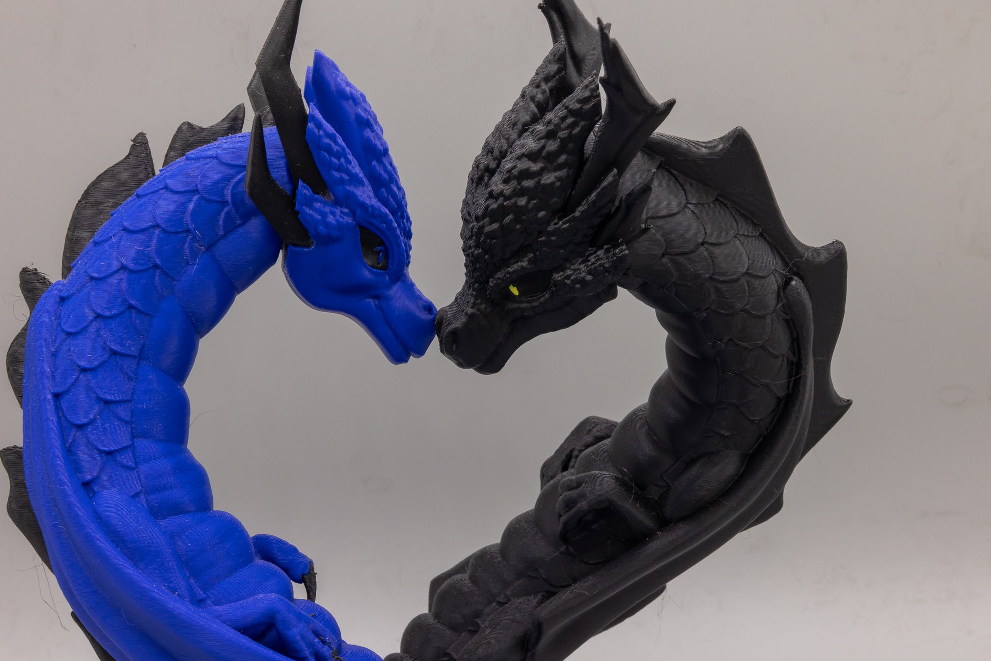 Close-up of the blue and black Draconic Bond dragons nose-to-nose forming a heart, 3D printed by MacPack3D